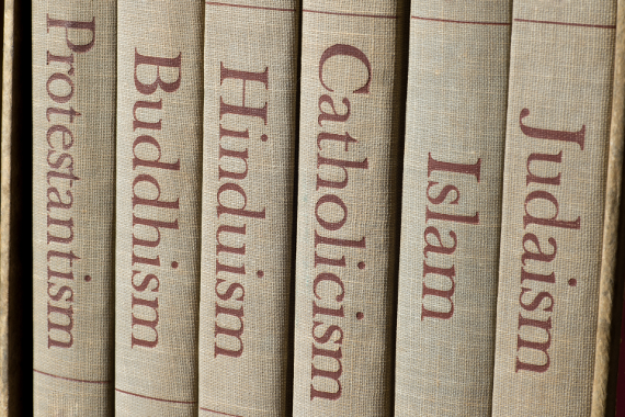 6 Bücher stehen nebeneinander, man sieht den Buchrücken, auf welchen steht: Protestantism, Buddhaism, Hinduism, Catholicism, Islam, Judaism