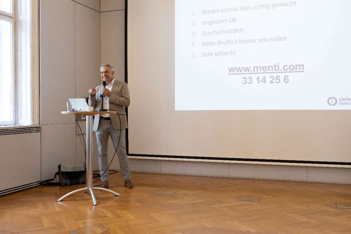 Dr.med. Gerald Gartlehner, MPH steht während seines Vortrags vor einer Leinwand mit Power Point Präsentation