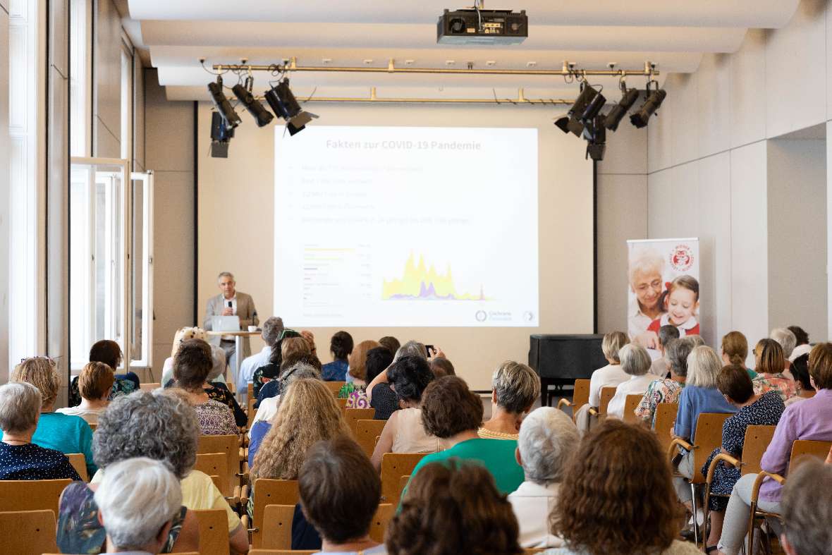 Das Publikum schaut auf Dr.med. Gerald Gartlehner, MPH und eine Leinwand mit Power Point Präsentation